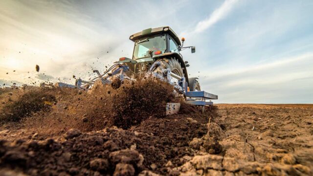 Traktor mit Anbaugerät beim Umgraben des Felds – Detailaufnahme mit Fokus auf Bodenstruktur und Maschinenkraft. Zuverlässige CNC Anlagen für Land- und Baumaschinenbau