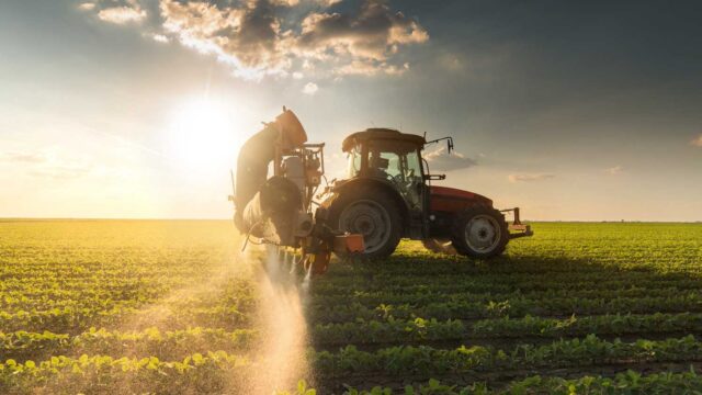 Traktor mit Sprühtechnik bei der Ausbringung im Feld – Anwendung von Pflanzenschutz im landwirtschaftlichen Alltag - HG GRIMME SysTech liefert dafür CNC Anlagen für den Land- und Baumaschinenbau
